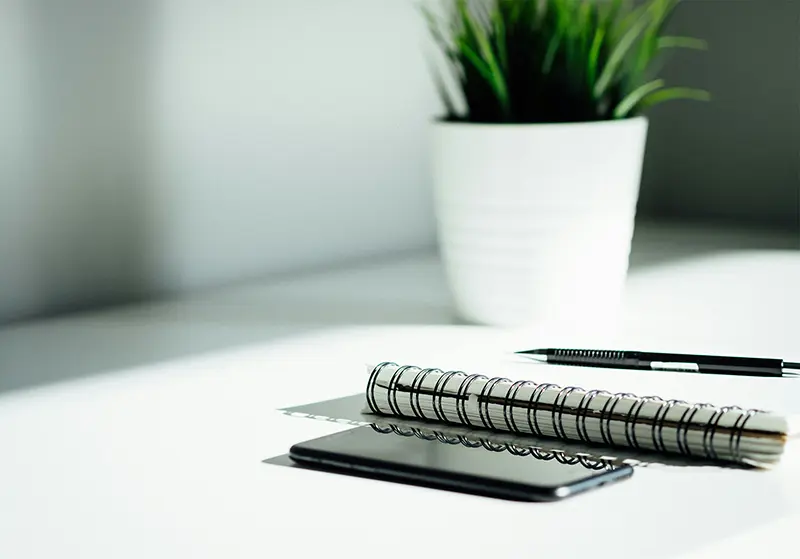 Foto von Handy, Block, Stift und Pflanze